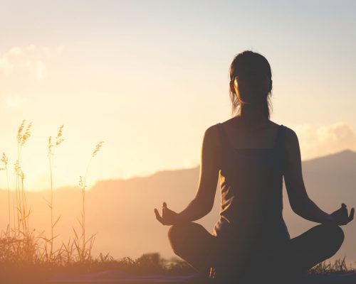 silhouette fitness girl practicing yoga on mountain with sun light