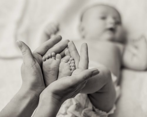 Mother holding tiny foot of newborn baby